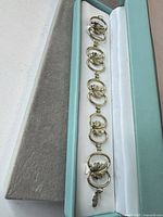 Bracelet in presentation box showing leaf motif links, clasp, safety chain