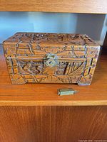 Front view of carved wooden box with latch and key shown