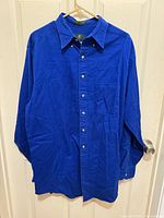 Front view of royal blue button-up shirt on hanger
