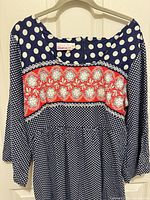 Front upper portion showing brand label, polka-dot bodice, red floral panel, long sleeves