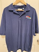 Front view of navy FeatherLite polo with embroidered flag logo