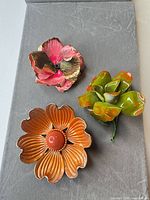 All three floral enamel brooches displayed together