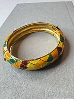 Full view of bangle bracelet showing mosaic enamel pattern and gold-tone interior