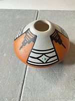 Top and side view of signed Hopi pot showing painted design and turquoise inlay