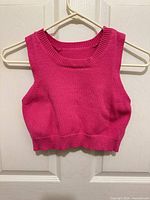 Front view of hot pink cropped sweater vest on hanger