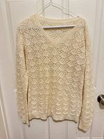 Front view of ivory lace knit sweater on hanger