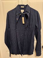 Front view of navy linen button-down shirt hanging, tag visible