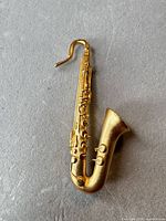 Front view of gold-tone saxophone brooch