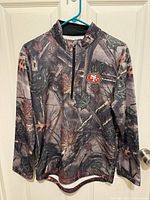 Front view of camo 49ers quarter-zip fleece on hanger