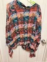 Front view of geometric multicolor oversized top on hanger