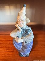 Front view of porcelain clown jester figurine on wooden surface