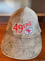 Front view showing embroidered 49ERS wordmark and logo, distressed faux leather surface