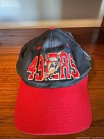 Front view of black and red 49ers cap with Tasmanian Devil embroidery