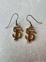 Front view of both gold-tone San Francisco Giants logo drop earrings with fishhook wires