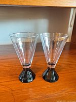 Front view of both clear conical goblets with black faceted bases