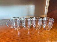 Four clear double-walled glass mugs lined up