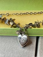 Necklace with heart locket pendant and small heart charms on display