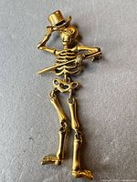 Front view of articulated skeleton brooch tipping top hat
