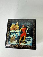 Top view showing painted Russian folk scene, gold border, glossy black lacquer