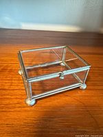 Oblique view showing glass panels, metal frame, ball feet, clasp