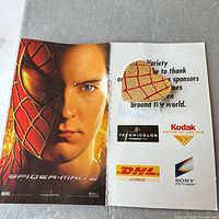 Back of Spider-Man 2 promotional card with half Spider-Man/half Peter Parker image and attached pin