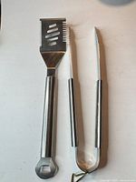 Full view of both stainless steel tools, spatula and tongs