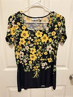 Front view of floral Susan Graver top on hanger