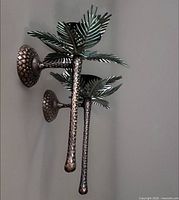 Side view of one sconce mounted showing pineapple backplate, textured arm and palm fronds