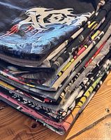 Stack of folded band T-shirts showing edge graphics and colours