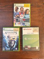 Front view of three Xbox 360 game cases: FIFA 08, Assassin's Creed, Overlord