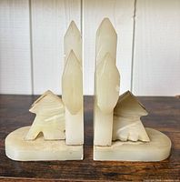 Front view of both alabaster bookends showing obelisk spires and animal figures