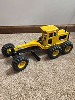 Left side view of Tonka grader showing six tires, cab, blade