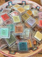 Bowl filled with numerous single-cube wax melt clamshells showing overall quantity and mix