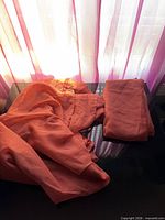 Folded and unfolded rust color sheer panels on table