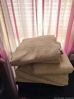 Stack of folded beige-taupe woven curtain panels in front of window