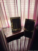 Two black and gold metal frames on top of a burgundy photo album