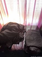 Pair of folded black sheer panels on table back-lit by window