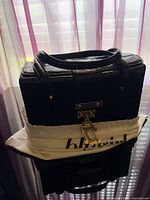 Front view of handbag with dust bag, shows croc texture, gold hardware, top handles