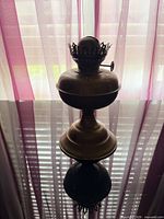 Full side view of brass oil lamp on reflective surface