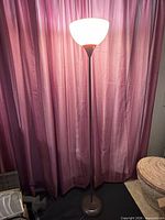 Full view of torchiere lamp lit, showing base, pole and shade