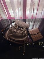 Front view of brown backpack and tan crossbody bag placed together