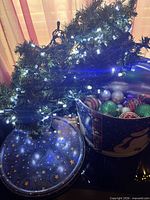 Garland lit, ornaments inside tin, tin lid visible