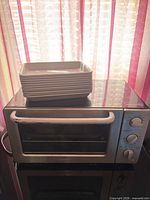 Front view of toaster oven with stack of pans on top