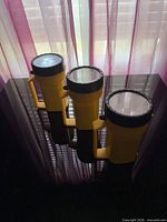Three yellow flashlights standing upright showing lenses
