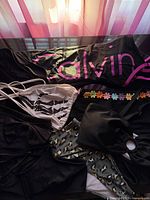 Group shot showing Calvin Klein one-piece, bikini tops, bottoms and daisy strap