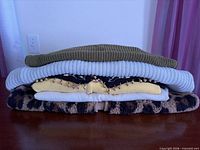 Stacked view of six folded tops showing colors and textures