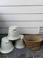 Four stacked large beige plastic pots beside woven basket