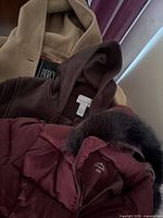 Three coats layered showing colors, materials, brand tags visible