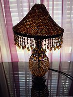 Full view of beaded table lamp on reflective surface