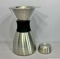 Coffee maker assembled with filter inserted, lid beside